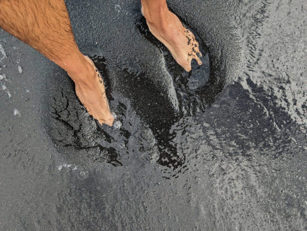 Feet on Black Sand Beach at Waiʻānapanapa State Park Road to Hana Maui Hawaii