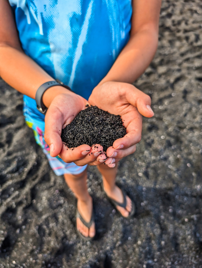 Taylor Family with handful of black sand at Punaluu Black Sand Beach Big Island Hawaii
